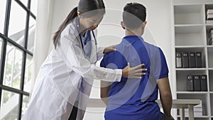 Female doctor giving male patient physiotherapy with hand lift, Asian female physiotherapist working