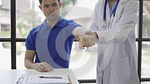 Female doctor giving male patient physiotherapy with hand lift, Asian female physiotherapist working