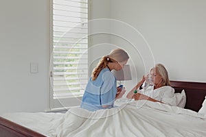 Female doctor giving medicine to active senior woman in bedroom