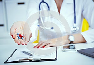 Female doctor hand doctor holding out colored pills.