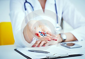 Female doctor hand doctor holding out colored pills.