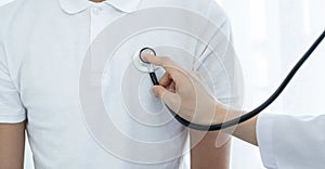 Female doctor hand examining the health of male patients chest with a stethoscope