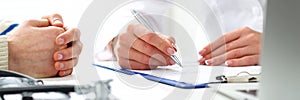 Female doctor hand hold silver pen filling patient history list