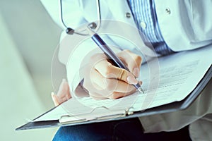 Female doctor hand hold silver pen filling patient history list at clipboard pad. Panacea and life save, prescribing