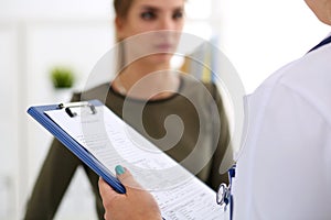 Female doctor hand holding and filling patient history list