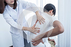 Female doctor hands doing physical therapy By extending the back of a male patient