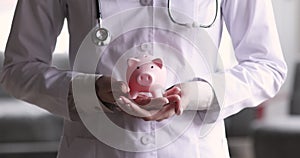 Female doctor hands holding piggy bank, healthcare donation concept