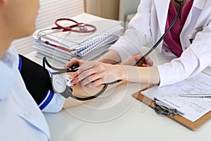 Female doctor hands measuring blood pressure to male patient