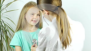 A female doctor hearing heartbeat of cute young girl. Review of a child in a pediatrician