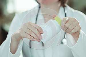 Female doctor holding bottle of dietary supplement