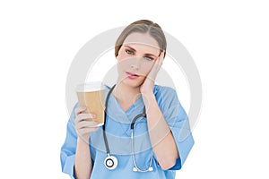 Female doctor holding a coffee mug and lifting her hand to her face