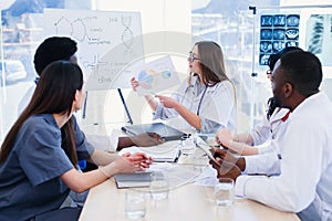 Female doctor holding in hands x ray result on the meeting at modern clinic.. Professional doctors of multi ethnic group