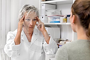 Female doctor holding her temporal, demonstration of headache or neuralgia pain