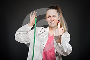 Female doctor holding measuring tape showing obscene gesture