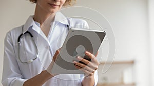 Female doctor holding modern pad using digital tablet applications, closeup