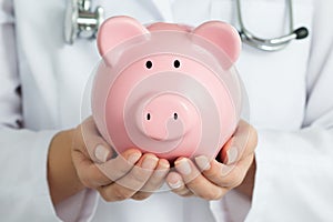 Female Doctor Holding Piggy Bank