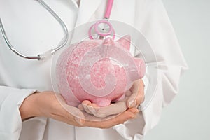 Female doctor holding piggy bank, closeup