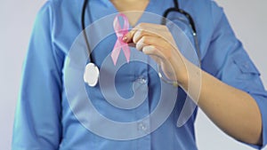 Female doctor holding pink ribbon, international breast cancer awareness symbol