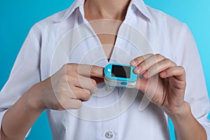 Female doctor holding pulsimeter on color background