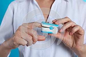 Female doctor holding pulsimeter on color background, closeup.