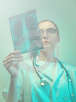 Female doctor holding X-ray of lungs, fluorography, roentgen in hospital. Woman in medical gown, stethoscope in consulting room.