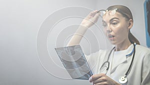 Female doctor holding X-ray of lungs, fluorography, roentgen in hospital. Woman in medical gown, stethoscope in consulting room.