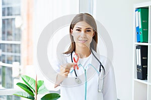 Female doctor holding a red ribbon as a symbol of AIDS