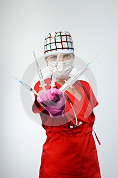 Female doctor holding several syringes in front of face.