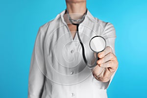 Female doctor holding stethoscope on color background