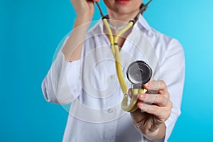 Female doctor holding stethoscope on color background