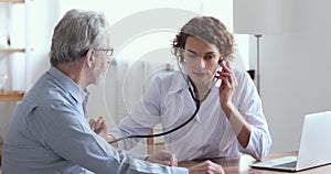 Female doctor holding stethoscope examining senior patient in hospital