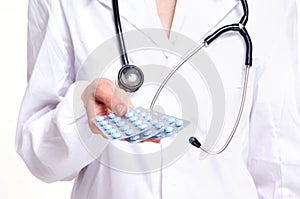 A female doctor holding three packs of pills