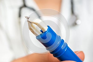 Female doctor is holding tweezers with a tick
