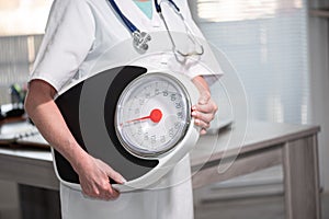 Female doctor holding a weight scale