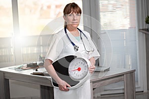 Female doctor holding a weight scale