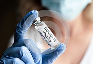 Female doctor holds bottle with COVID-19 coronavirus vaccine in laboratory