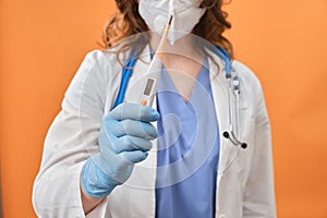 A female doctor holds an electronic digital thermometer in her hand. Medical instrument for measuring body temperature, studio