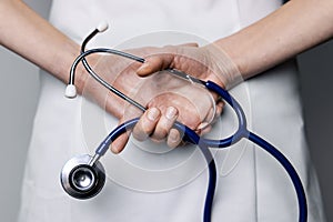 Female doctor holds stethoscope in hands behind back