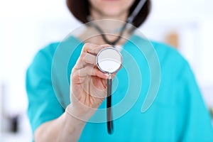 Female doctor holds stethoscope head closeup. Physicians ready to examine and help patient. Medical help and insurance