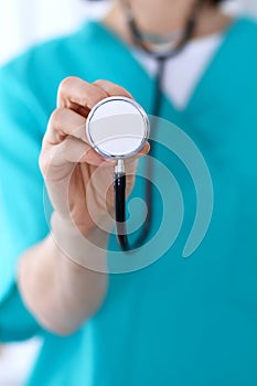 Female doctor holds stethoscope head closeup. Physicians ready to examine and help patient. Medical help and insurance