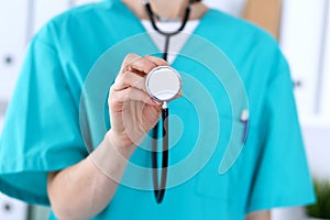 Female doctor holds stethoscope head closeup. Physicians ready to examine and help patient. Medical help and insurance