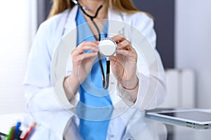 Female doctor holds stethoscope head, just hands closeup. Physician ready to examine and help patient. Medical help and