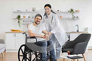 Female doctor hugging smiling male patient with disability posing at home.