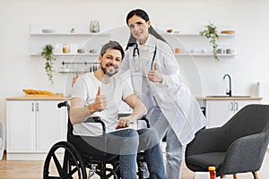 Female doctor hugging smiling male patient with disability posing at home.