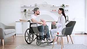 Female doctor hugging smiling male patient with disability posing at home.