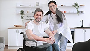 Female doctor hugging smiling male patient with disability posing at home.