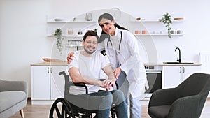 Female doctor hugging smiling male patient with disability posing at home.