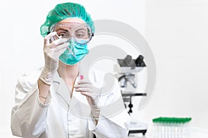 Female doctor in the laboratory with a blood tube for analysis and sampling of Coronavirus under the microscope.