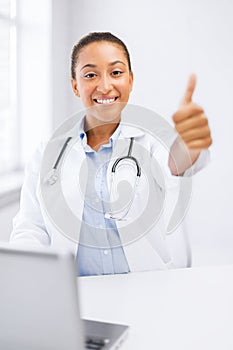 Female doctor with laptop showing thumbs up