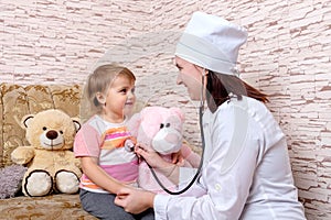 Female doctor is listening to child with stethoscope at home